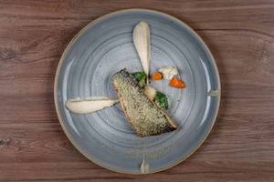 Teller mit Fisch und Gemüse auf einer Holzoberfläche.