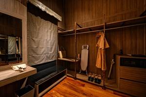 Innenansicht eines Zimmers im Kalima Resort & Villas Khao Lak, mit Garderobe, Bügelbrett und Schuhen.