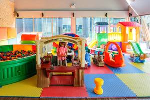 Ein buntes Kinderspielzimmer im Kalima Resort & Villas Khao Lak mit verschiedenen Spielgeräten und einer Spielküche.