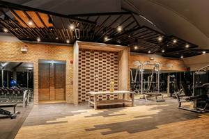 Fitness Center im Kalima Resort & Villas Khao Lak mit Holzboden, Ziegelwänden und Fitnessgeräten.