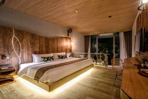 Inneneinrichtung des Zimmers im Kalima Resort & Villas Khao Lak mit Holzwänden und Möbeln.