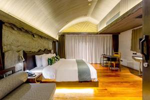 Ein modernes Schlafzimmer mit einem großen Bett, einem Schreibtisch und einem Sofa im Kalima Resort & Villas Khao Lak.