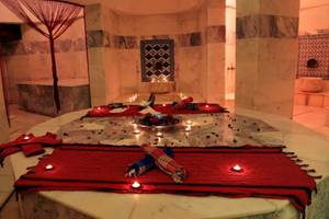 Innenansicht des LABRANDA Ephesus Princess Hammam mit rotem Teppich, Kerzen und Marmorwänden.