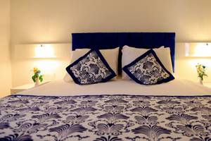 Bett im LABRANDA Ephesus Princess Hotel mit blau-weißem Design und Blumenvasen auf Nachttischen.