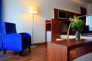 Hotelzimmer im Labranda Ephesus Princess mit blauem Sessel, Lampe und Tisch mit Blumen.