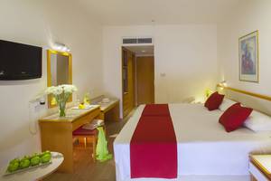 Hotelzimmer im Queens Bay mit zwei Betten, Dekor und Einrichtungsgegenständen.