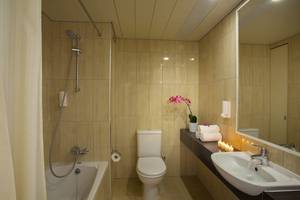 Badezimmer im Queens Bay Hotel mit Badewanne, Toilette, Waschbecken und Spiegel.