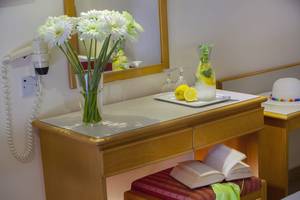 Zimmer im Queens Bay Hotel mit Blumen, offenem Buch und gefülltem Glas