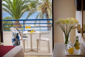 Terrasse des Queens Bay Hotels mit Blick auf das Meer und Palmenbäume.