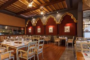Innenbereich des Restaurants im Kempinski Hotel The Dome Belek mit Holzboden und weißen Stühlen.