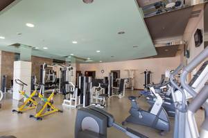 Fitnessstudio im Kempinski Hotel The Dome Belek mit verschiedenen Trainingsgeräten und einem hellen Innenraum.