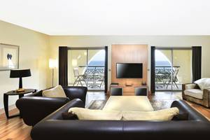 Wohnzimmer im Kempinski Hotel The Dome Belek mit Fernseher, Sofas und Blick aufs Meer.