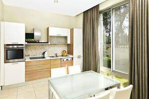 Innenansicht der Küche im Kempinski Hotel The Dome Belek mit moderner Ausstattung und Glastisch.