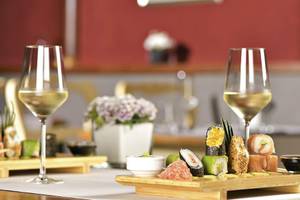 Ein Tisch mit Sushi-Platten, Wein und Weinglas in einem Restaurant.