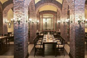Innenansicht des Restaurants im Kempinski Hotel The Dome Belek mit roten Ziegelwänden und runden Säulen.