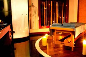 Spa-Behandlungsraum im Kempinski Hotel The Dome Belek mit Massagetisch, blauen Handtüchern und brennenden Kerzen.