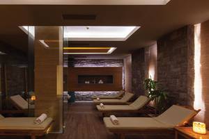 Sauna Bereich im Kempinski Hotel The Dome Belek mit Holzliegen und Steinwänden.