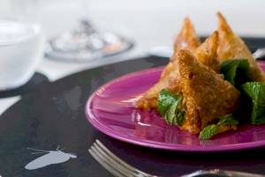 Eine violette Platte mit frittierten Dreiecken und Minzblättern, serviert im Barcelo Raval Hotel.