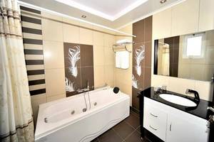 Badezimmer im Gaia Palace Hotel mit Badewanne und modernem Design.