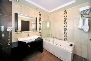 Badezimmer im Gaia Palace Hotel mit Badewanne, Waschbecken und Spiegel