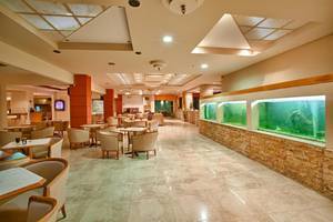 Loungebereich des Ilios K. Village Resorts mit Tischen, Stühlen und großen Aquarien.