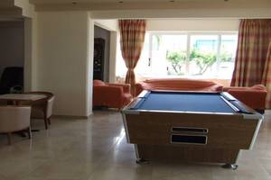 Pooltisch in der Lobby des Ilios K. Village Resort, umgeben von Sofas und Sesseln.