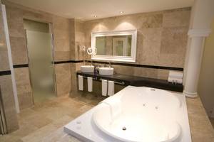 Badezimmer im Grand Riviera Princess Hotel mit Badewanne, Spiegel und Waschbecken.