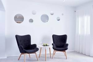 Lobby Sitzecke im Absolute Mykonos Suites & More Hotel mit weißen Wänden und runden Spiegeln.