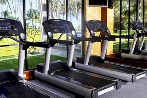 Fitnessstudio im Blue Water Hotel mit mehreren Laufbändern vor großen Fenstern.