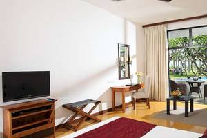 Hotelzimmer mit modernem Interieur, Fernseher, Schreibtisch und Blick auf einen Swimmingpool.