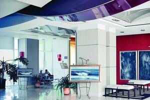 Empfangsbereich des Festa Panorama Hotels mit roter Wand, Kunstwerken und Sitzgelegenheiten.