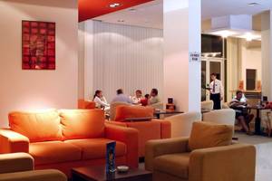 Lobby des Festa Panorama Hotels mit orangefarbenen Sofas, Gästen und einem Barbereich.