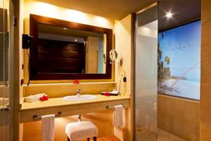 Badezimmer mit Spiegel, Waschbecken und Glasdusche, Blick auf den Strand.