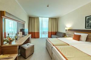 Doppelzimmer im Festa Panorama Hotel mit zwei Betten, Schreibtisch, Spiegel, Sofa und Fenstern.