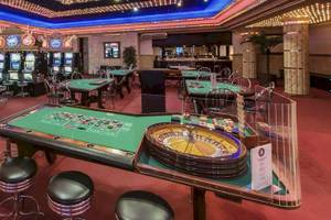 Spielbereich im Casino des Catalonia Royal Bavaro Hotels mit Roulettetisch, Spielautomaten und Tischen.