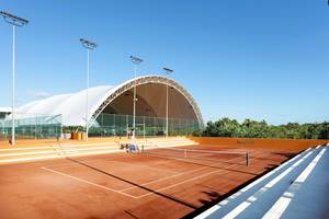 Tennisanlage im Grand Palladium Costa Mujeres Resort & Spa mit blauem Himmel und orangefarbenen Wänden.