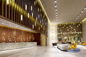 Empfangsbereich des Grand Palladium Costa Mujeres Resort & Spa mit Marmorrezeption und leuchtenden Wandverkleidungen.