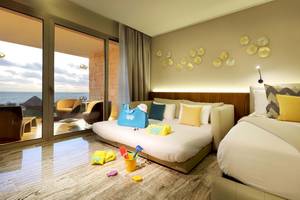 Zimmer im Grand Palladium Costa Mujeres Resort & Spa mit Meerblick, zwei Betten, Möbeln und Spielzeug.