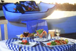 Ein Tisch im Restaurant des LABRANDA Club Makadi mit verschiedenen Gerichten und Getränken, darunter ein Fischboot im Hintergrund.