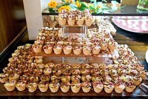 Viele Cupcakes in verschiedenen Farben und Dekorierungen auf mehreren Ebenen in einem Hotel.