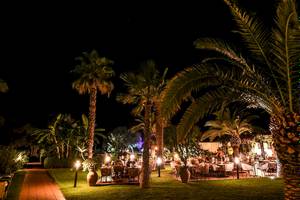Foto von Baia del Sole Hotel Garten bei Nacht mit beleuchteten Tischen und Palmen