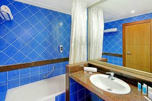 Badezimmer im Mirador Papagayo by LIVVO Hotel mit blauen Fliesen und Badewanne