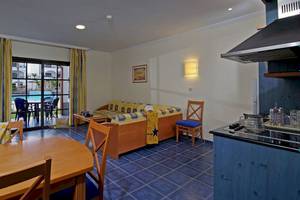 Einrichtung eines Zimmers im Mirador Papagayo by LIVVO Hotel mit Wohnzimmer, Esstisch und Küche.