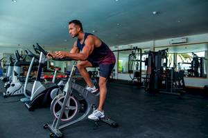 Ein Mann trainiert auf einem Indoor-Fahrrad im Fitnessstudio.