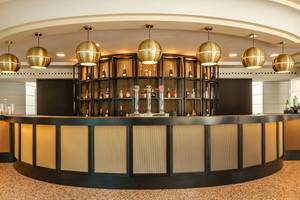 Lobby Bar im Sarena de Muro Resort Mallorca mit goldenen Kronleuchtern und einer großen Bartheken.