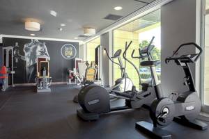 Fitnessstudio im Sarena de Muro Resort Mallorca mit Technogym-Geräten und Blick auf die Außenlandschaft.
