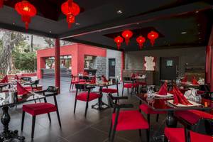Innenbereich des Voyage Sorgun Restaurants mit roten Stühlen und Tischen, chinesischen Laternen und einer offenen Aussicht auf den Außenbereich.