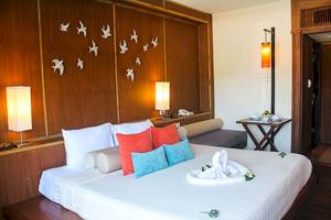 Schlafzimmer im Seaview Patong Hotel mit einem großen Bett, dekorativen Kissen und vogelförmigen Wanddekorationen.