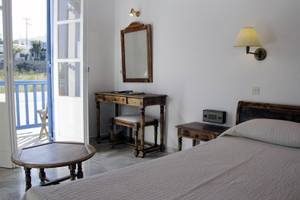 Ein Schlafzimmer mit Balkon und Holzmöbeln, einschließlich eines Bettes, eines Schreibtisches und eines Spiegels.