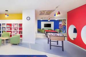 Das farbenfrohe Kinderzimmer des Hilton Ras Al Khaimah Beach Resort mit Bücherregalen, Tischen, Stühlen und Spielen.